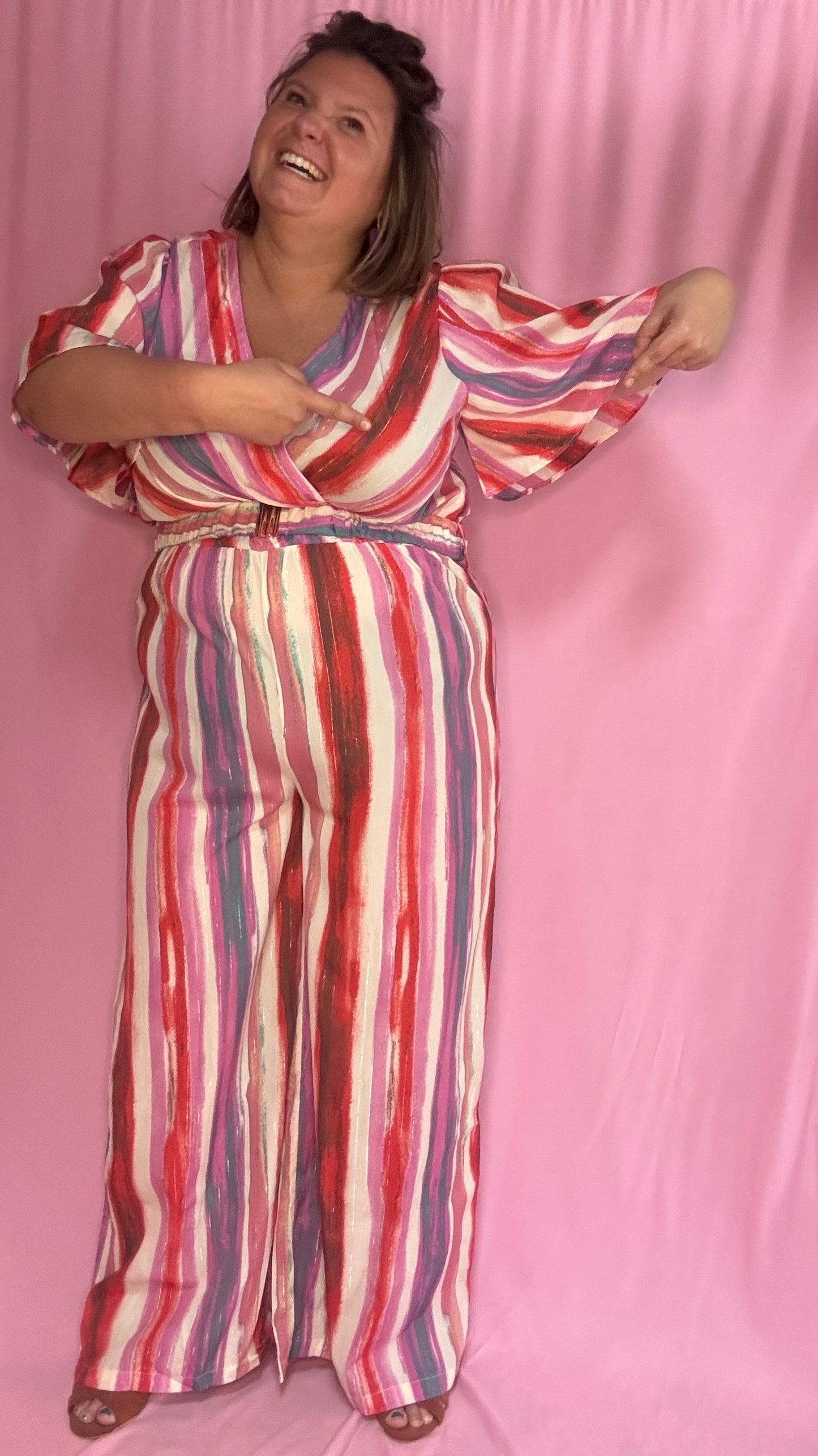 Cette combinaison grande taille aux motifs rayures verticales dans des tons roses, rouge, blanc et violet allonge visuellement la silhouette et attire tous les regards.