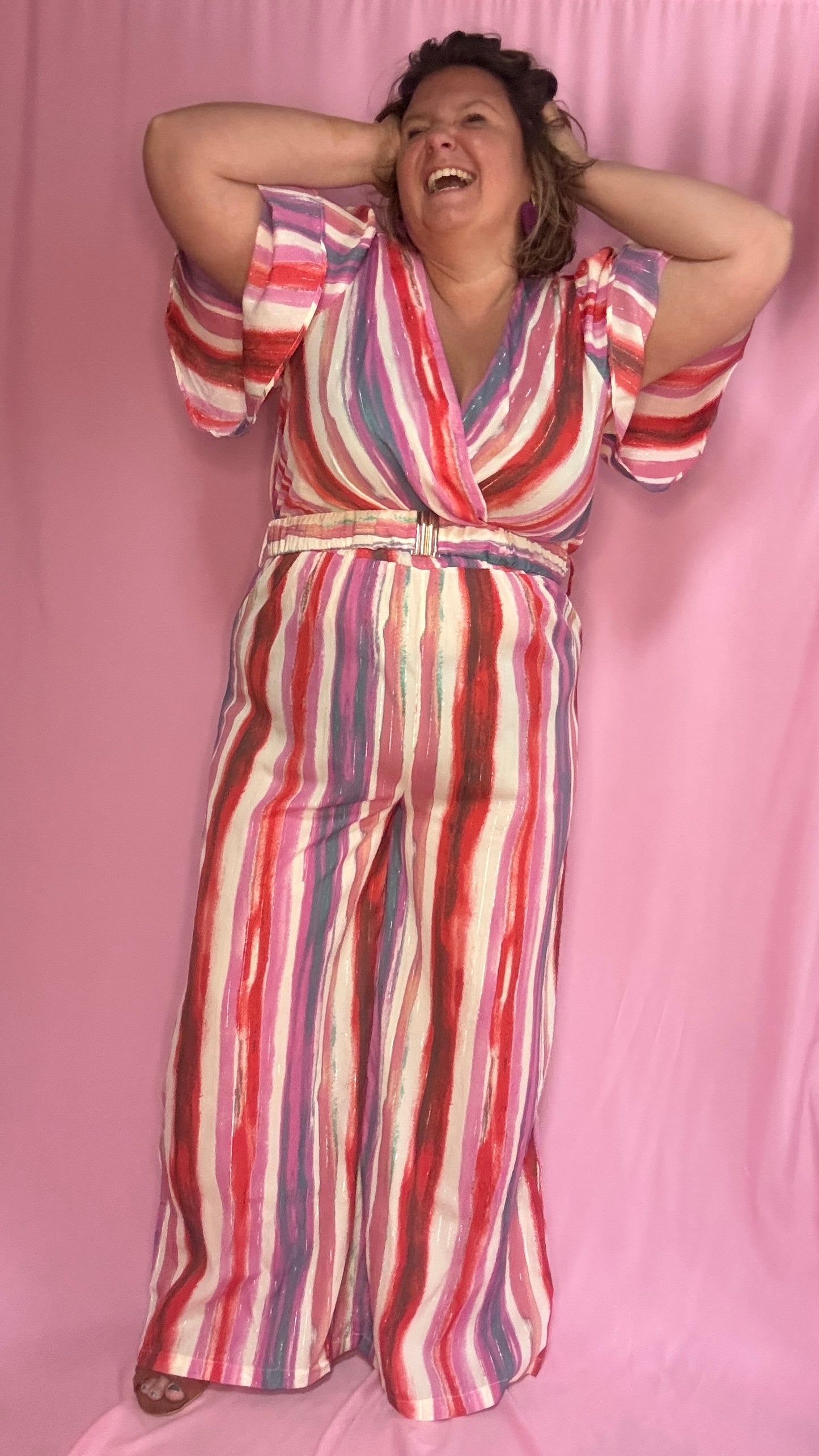 Cette combinaison grande taille aux motifs rayures verticales dans des tons roses, rouge, blanc et violet allonge visuellement la silhouette et attire tous les regards.