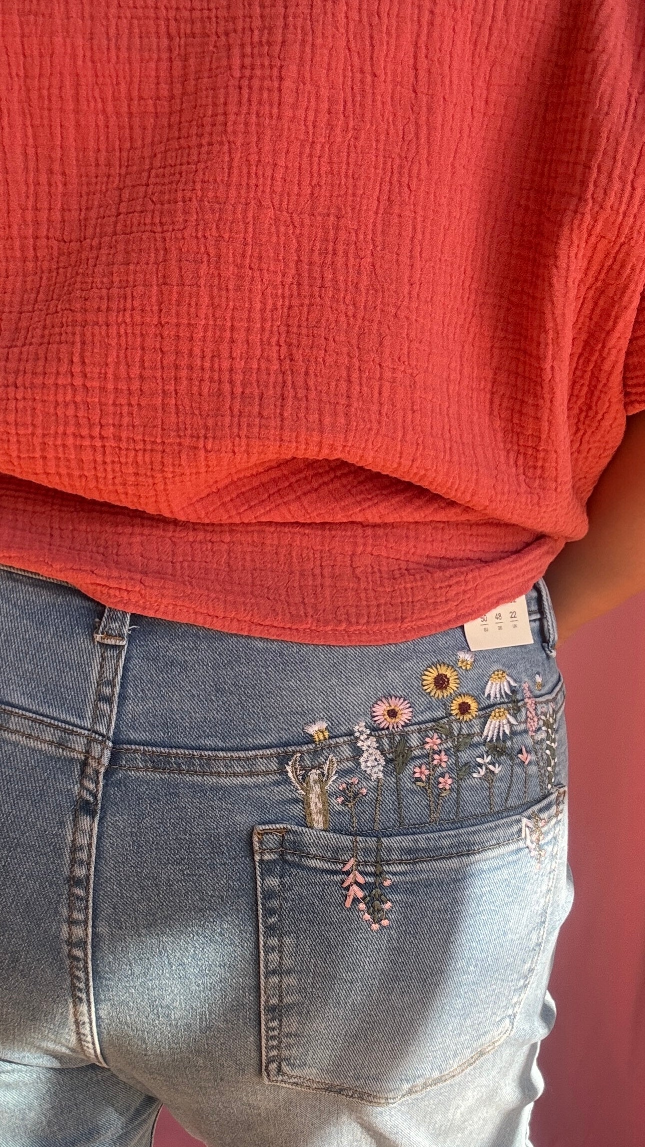 Un jean grande taille clair arty à souhait, avec son superbe détail de broderie fleurie colorée (rose, jaune…) brodée sur les fesses