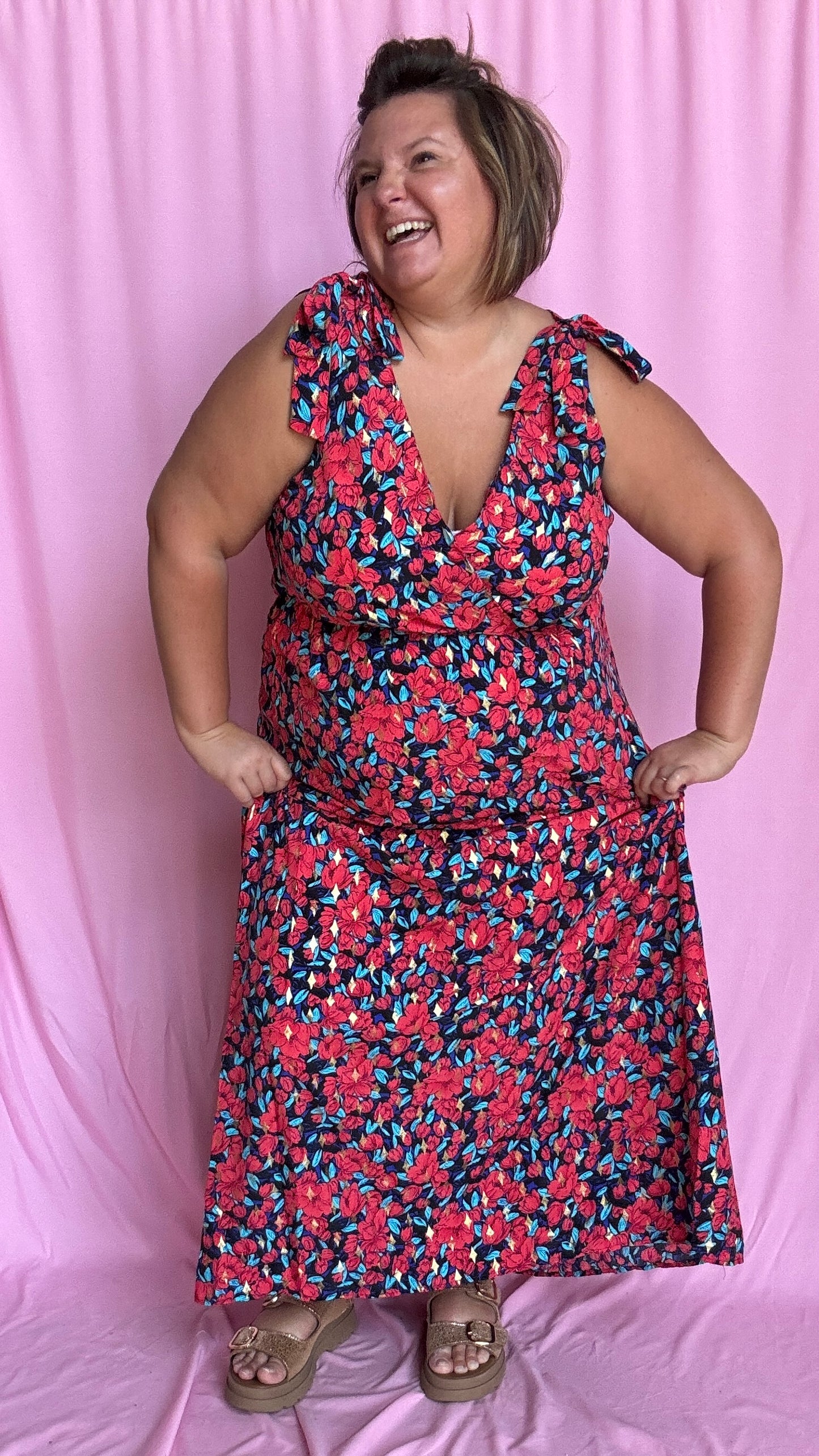 Une robe longue grande taille ultra féminine et pleine d'élégance, avec ses magnifiques motifs fleuris dans les tons rouge, bleu et doré et son dos nu.