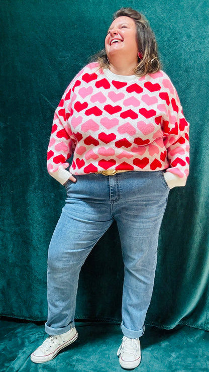 Ajoutez ce pull grande taille à motifs cœurs rouge et rose à votre collection pour allier douceur, originalité et style romantique tout en restant au chaud cet hiver.