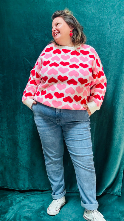 Ajoutez ce pull grande taille à motifs cœurs rouge et rose à votre collection pour allier douceur, originalité et style romantique tout en restant au chaud cet hiver.