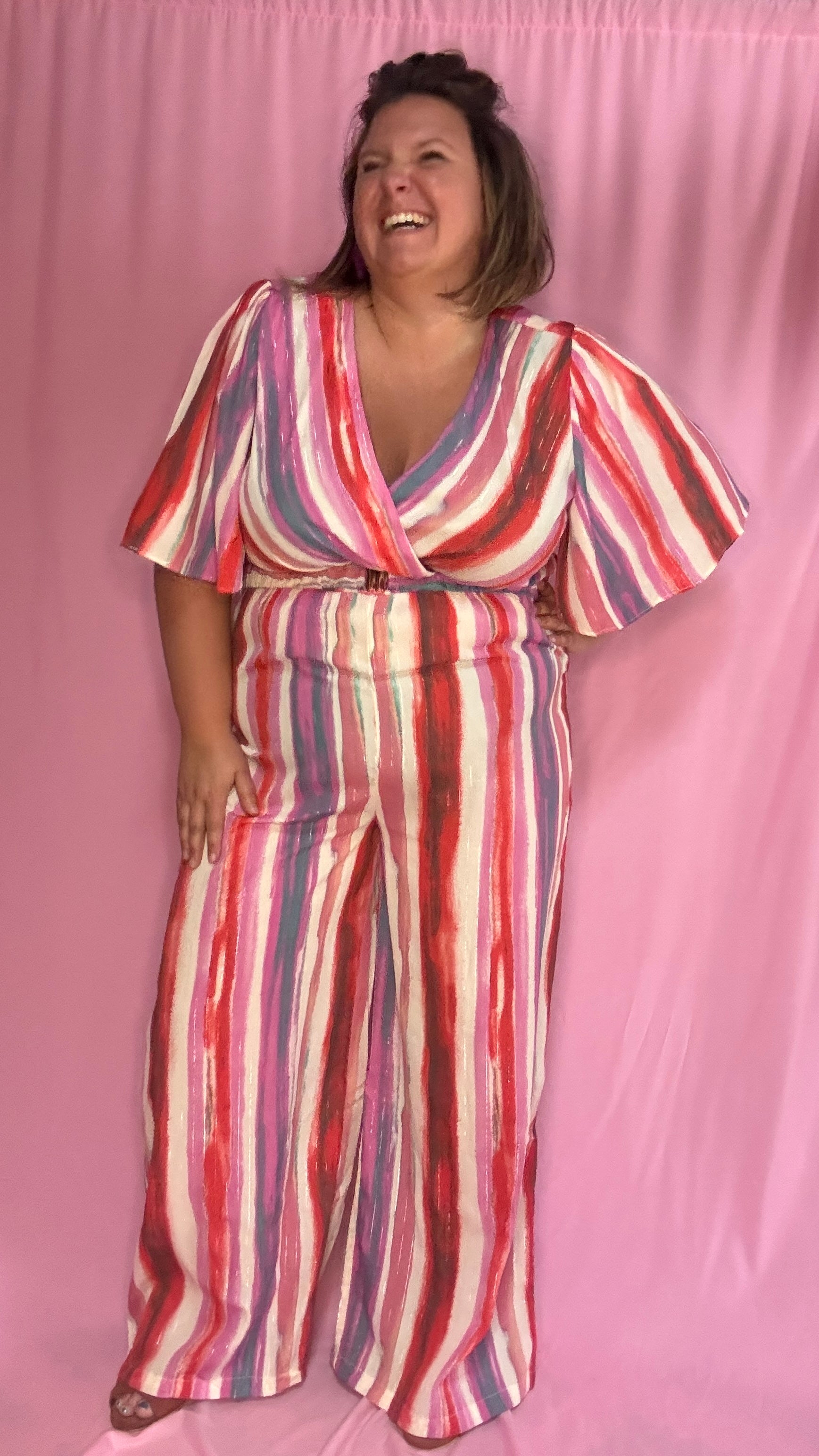 Cette combinaison grande taille aux motifs rayures verticales dans des tons roses, rouge, blanc et violet allonge visuellement la silhouette et attire tous les regards. 