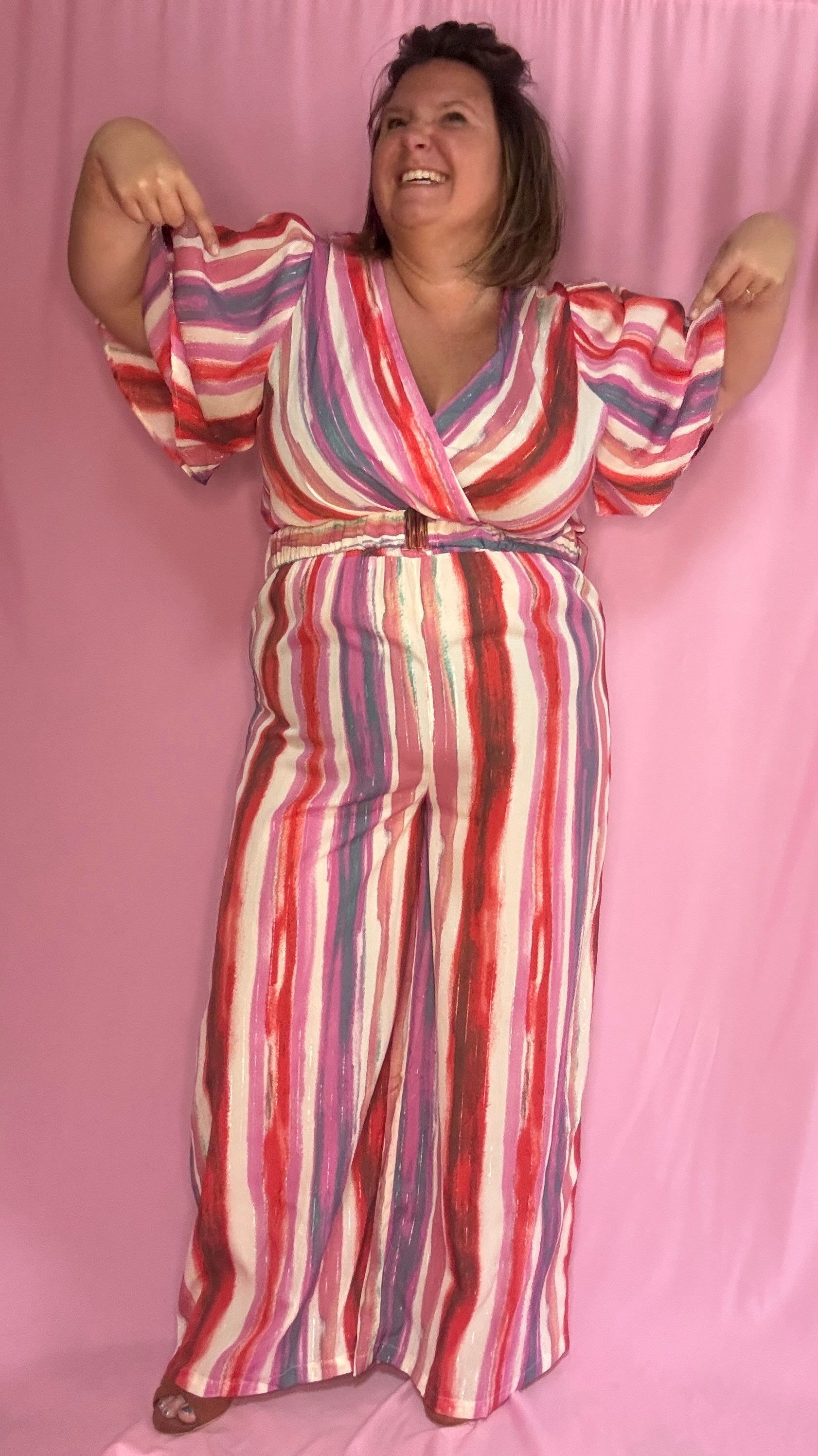 Cette combinaison grande taille aux motifs rayures verticales dans des tons roses, rouge, blanc et violet allonge visuellement la silhouette et attire tous les regards. 