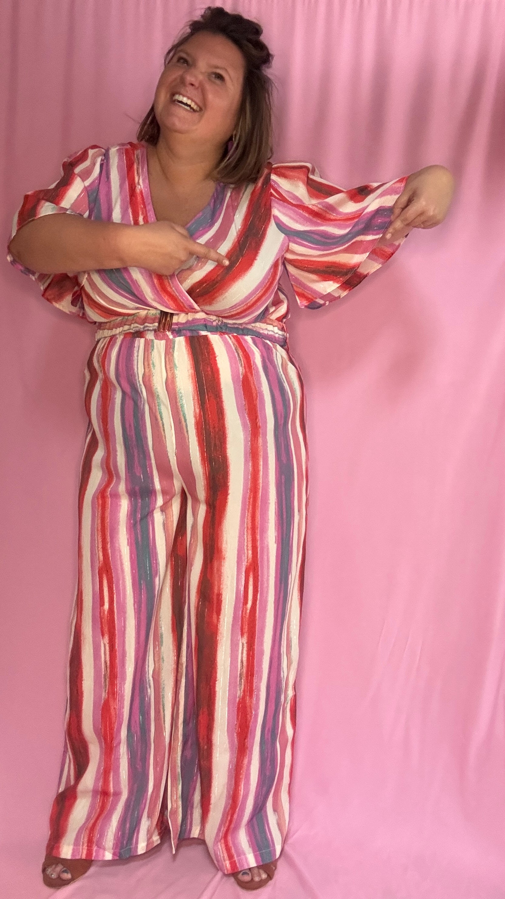 Cette combinaison grande taille aux motifs rayures verticales dans des tons roses, rouge, blanc et violet allonge visuellement la silhouette et attire tous les regards. 