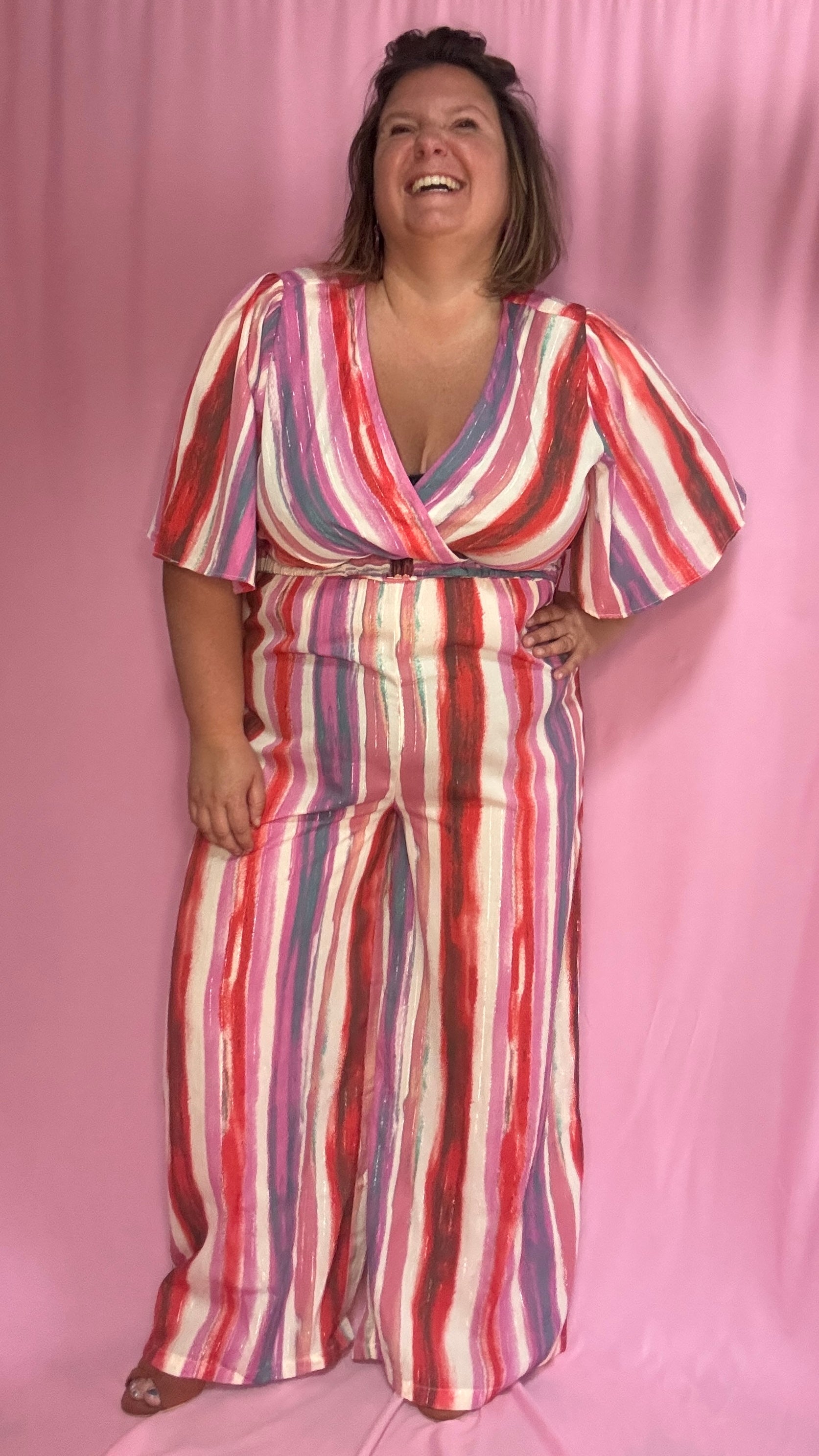 Cette combinaison grande taille aux motifs rayures verticales dans des tons roses, rouge, blanc et violet allonge visuellement la silhouette et attire tous les regards. 