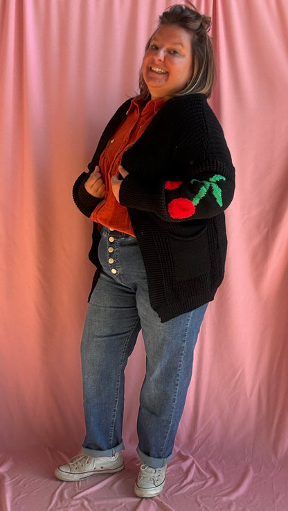 Ajoutez une dose de fun et de style à vos tenues avec ce gilet long grande taille noir, orné de gros motifs cerise sous les coudes pour une touche créative et pleine de pep’s.