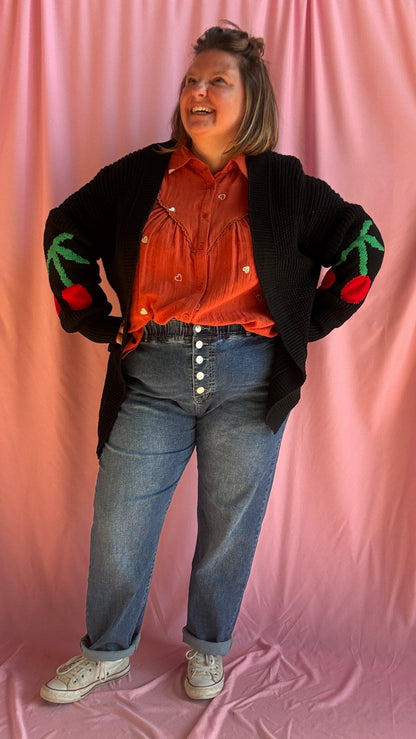 Ajoutez une dose de fun et de style à vos tenues avec ce gilet long grande taille noir, orné de gros motifs cerise sous les coudes pour une touche créative et pleine de pep’s.