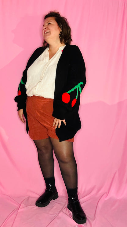 Ajoutez une dose de fun et de style à vos tenues avec ce gilet long grande taille noir, orné de gros motifs cerise sous les coudes pour une touche créative et pleine de pep’s.