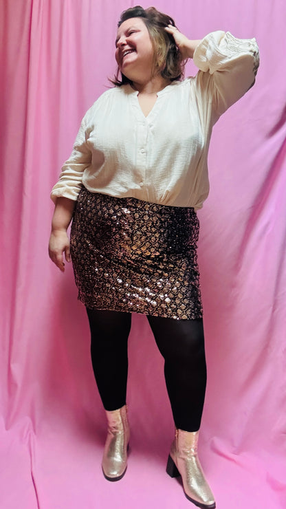 Cette mini jupe grande taille à sequins dorés et bronze est un atout incontournable pour toutes les femmes qui souhaitent briller et se démarquer. Confortable, pratique et éblouissante, elle sera votre meilleure alliée pour rayonner en toutes occasions !