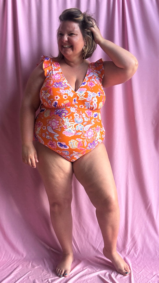 Soleil, plage et confiance en soi au rendez-vous avec ce superbe maillot de bain une pièce grande taille aux motifs fleuris dans des tons orange, rose, violet et blanc