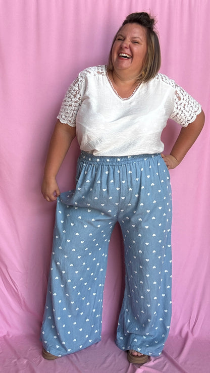Avec sa coupe droite et jambes larges, ce pantalon fluide bleu ciel motifs coeur blanc est parfait pour bouger librement tout en étant stylée.