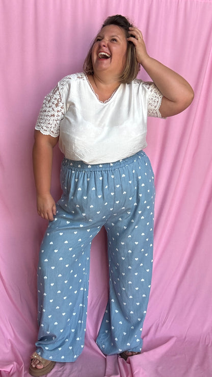 Avec sa coupe droite et jambes larges, ce pantalon fluide bleu ciel motifs coeur blanc est parfait pour bouger librement tout en étant stylée.