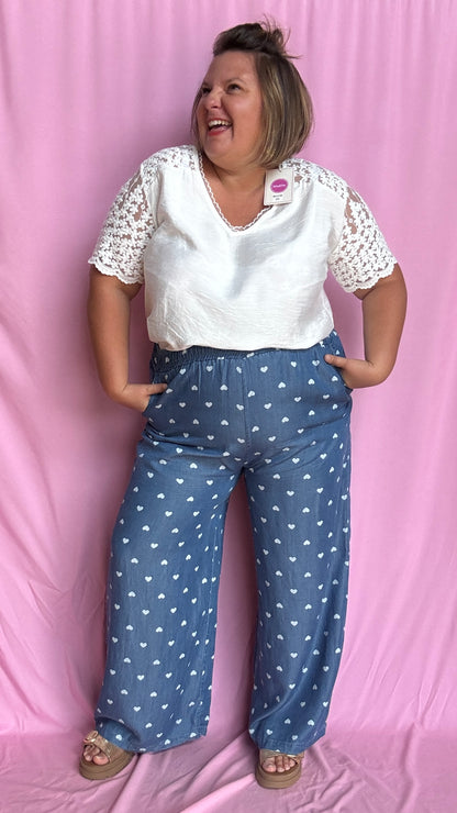 Avec sa coupe droite et jambes larges, ce pantalon fluide bleu jean motifs coeur blanc est parfait pour bouger librement tout en étant stylée.