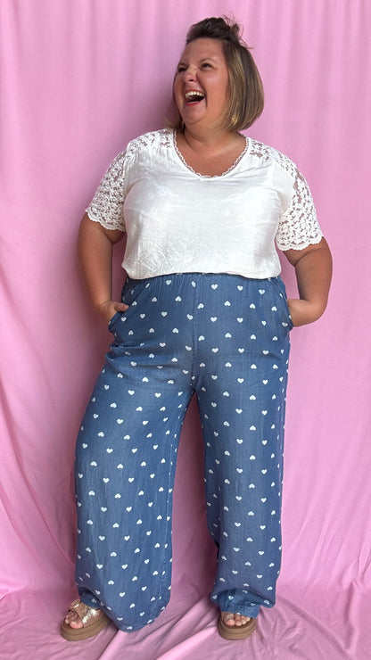 Avec sa coupe droite et jambes larges, ce pantalon fluide bleu jean motifs coeur blanc est parfait pour bouger librement tout en étant stylée.