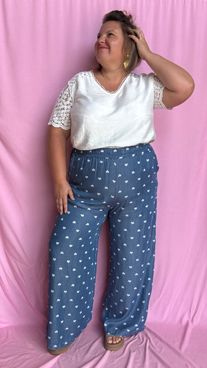 Avec sa coupe droite et jambes larges, ce pantalon fluide bleu jean motifs coeur blanc est parfait pour bouger librement tout en étant stylée.