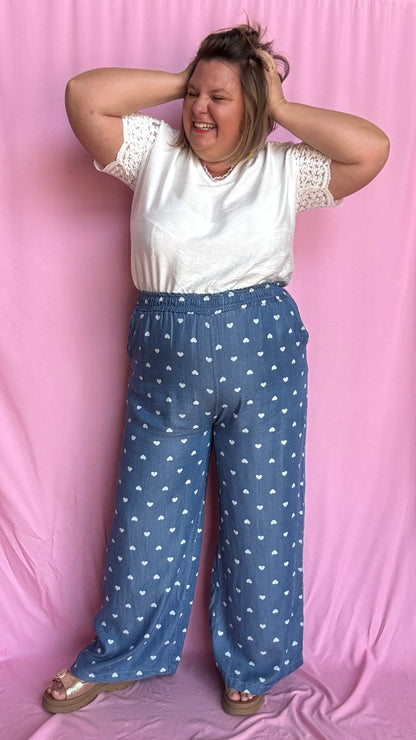 Avec sa coupe droite et jambes larges, ce pantalon fluide bleu jean motifs coeur blanc est parfait pour bouger librement tout en étant stylée.