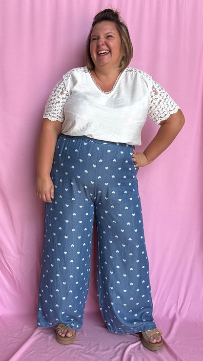Avec sa coupe droite et jambes larges, ce pantalon fluide bleu jean motifs coeur blanc est parfait pour bouger librement tout en étant stylée.