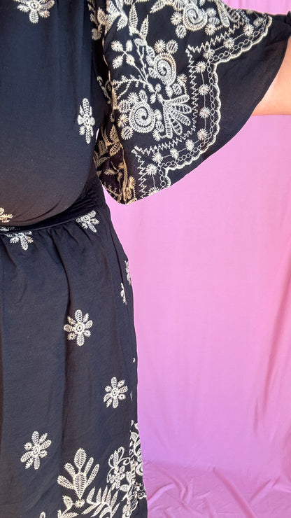 Craquez pour cette robe grande taille à manches courtes, aussi élégante que confortable, pensée pour sublimer toutes les morphologies avec style. Son motif brodé beige délicat contraste à merveille avec le fond noir, pour un rendu raffiné et moderne.