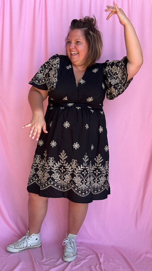 Craquez pour cette robe grande taille à manches courtes, aussi élégante que confortable, pensée pour sublimer toutes les morphologies avec style. Son motif brodé beige délicat contraste à merveille avec le fond noir, pour un rendu raffiné et moderne.