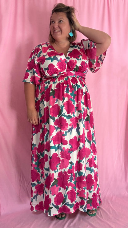 Laisse-toi séduire par cette robe longue grande taille aux motifs fleuris roses, verts et blancs, une pièce aussi délicate qu'élégante.