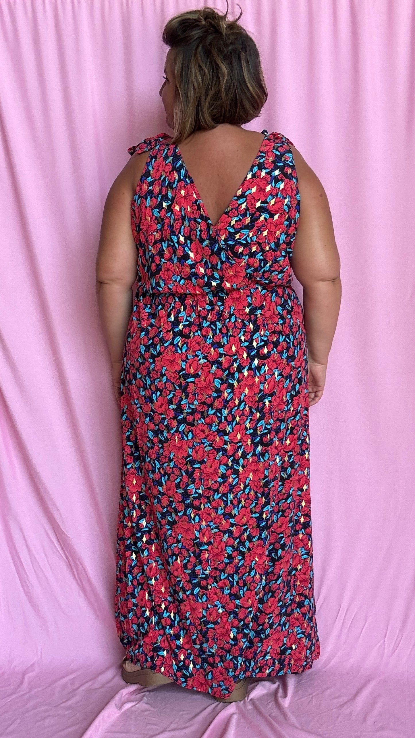 Une robe longue grande taille ultra féminine et pleine d'élégance, avec ses magnifiques motifs fleuris dans les tons rouge, bleu et doré et son dos nu.