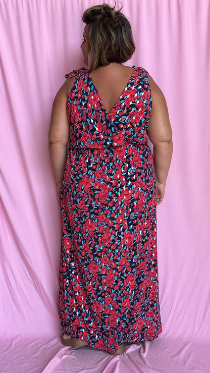 Une robe longue grande taille ultra féminine et pleine d'élégance, avec ses magnifiques motifs fleuris dans les tons rouge, bleu et doré et son dos nu.