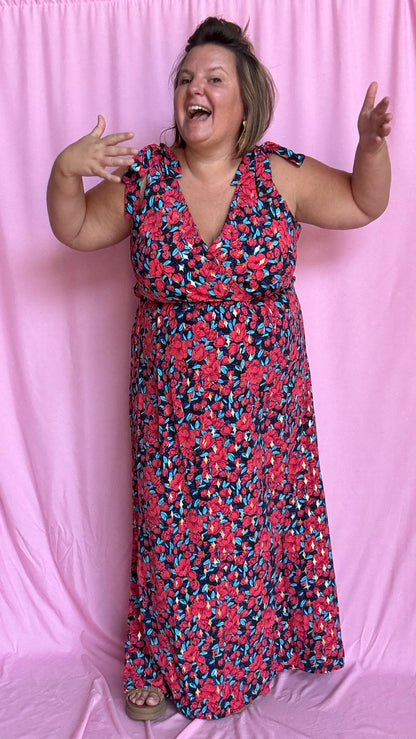 Une robe longue grande taille ultra féminine et pleine d'élégance, avec ses magnifiques motifs fleuris dans les tons rouge, bleu et doré et son dos nu.