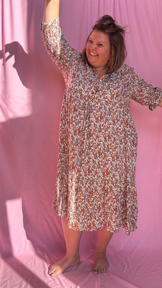 Laisse-toi séduire par cette robe longue grande taille aux motifs fleurs liberty dans des tons camel, beige et bleu ciel, à la fois doux et lumineux.