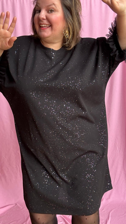 Une robe grande taille droite noir et paillettes manches évasées en froufrous pour un look arty glamour