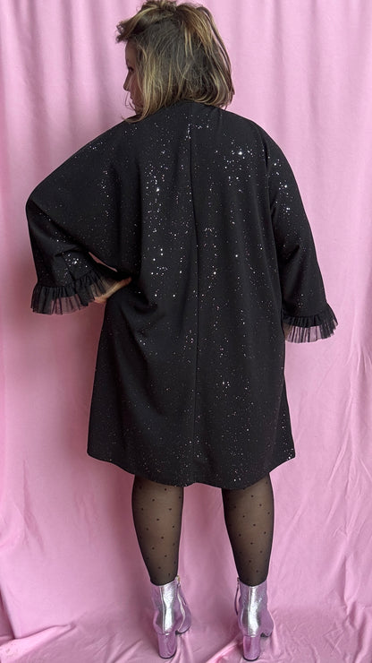 Une robe grande taille droite noir et paillettes manches évasées en froufrous pour un look arty glamour
