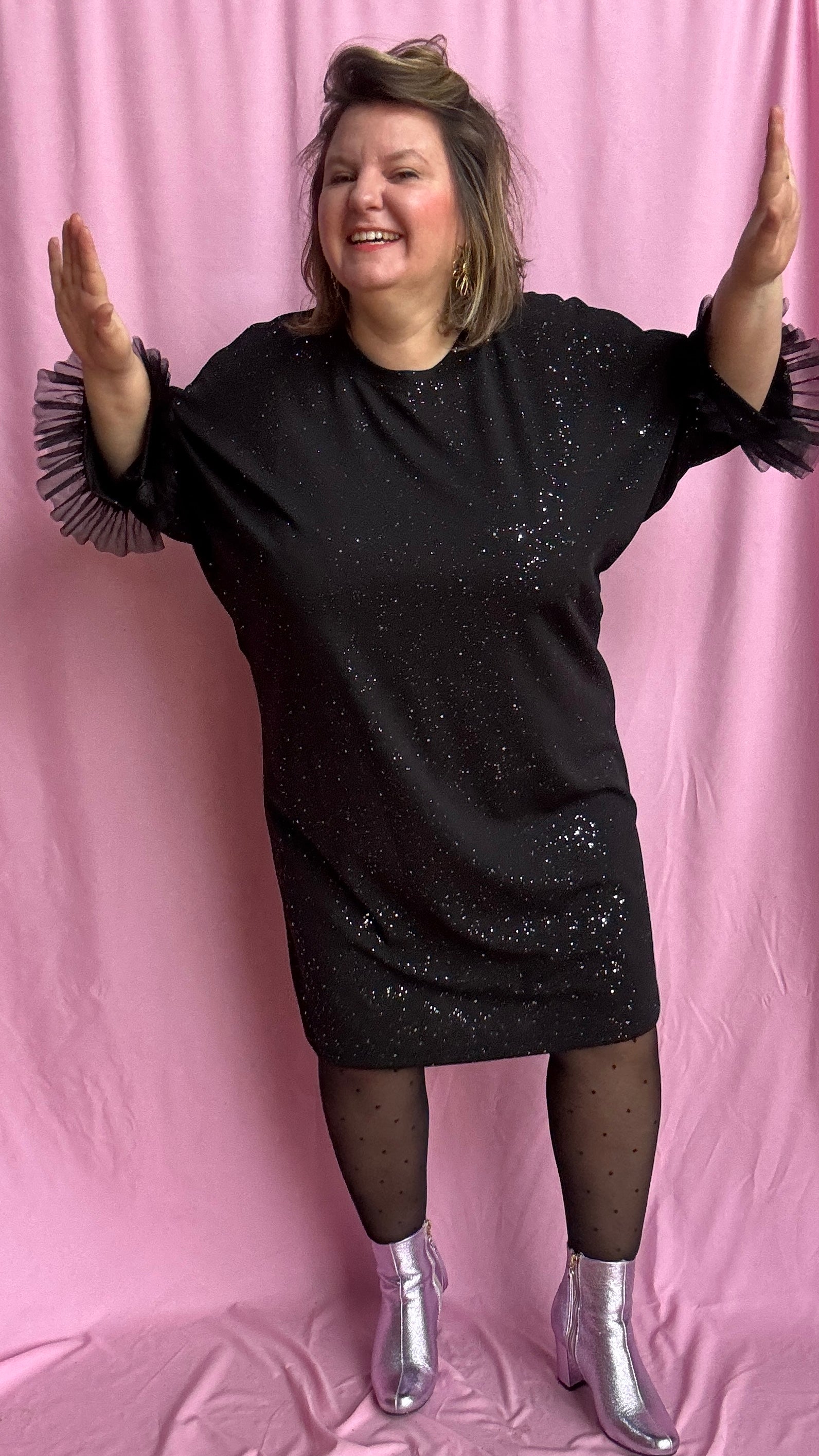 Une robe grande taille droite noir et paillettes manches évasées en froufrous pour un look arty glamour