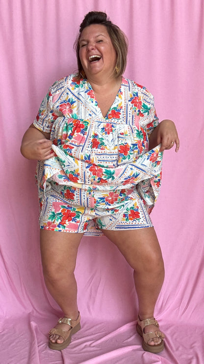 Une pièce ingénieuse et ultra stylée : cette robe-short grande taille aux motifs fleuris rouge vert bleu et jaune associe le confort d’un short à la féminité d’une robe courte droite